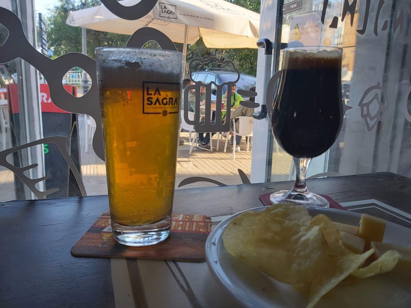 Variedad de cervezas en barra con patatas fritas y quesos